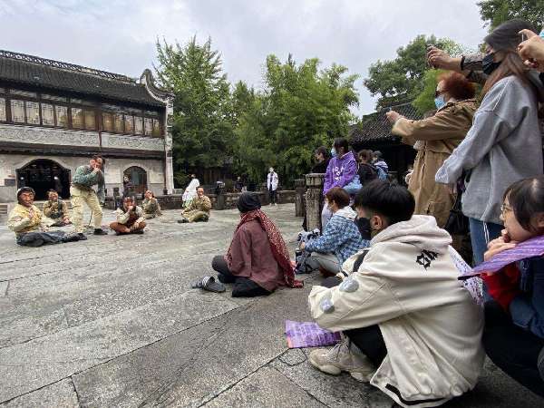 游客席地而坐，被古镇嘉年华的街头戏剧所吸引。 殷泓摄-光明图片