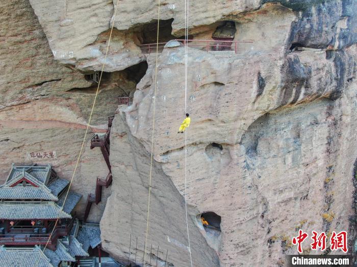 图为无人机航拍演职人员通过麻绳从山顶空降至崖洞内。　刘力鑫 摄