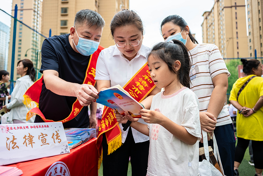 呼和浩特市玉泉区“爱在‘七夕’践文明 和谐家风共传承”主题文明市集活动现场，志愿者向小朋友普及未成年人保护法相关知识。丁根厚摄