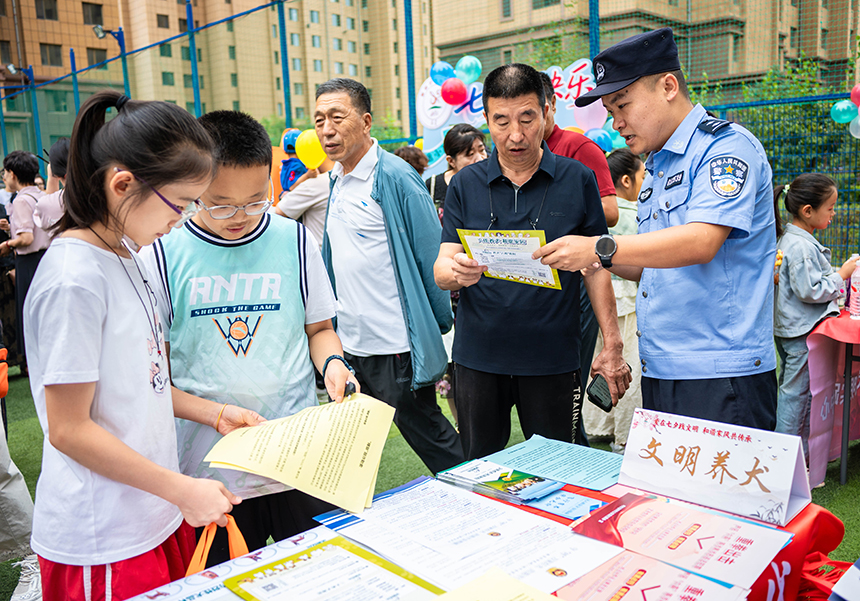 呼和浩特市玉泉区“爱在‘七夕’践文明 和谐家风共传承”主题文明市集活动现场，民警向市民发放文明养犬宣传资料。丁根厚 摄